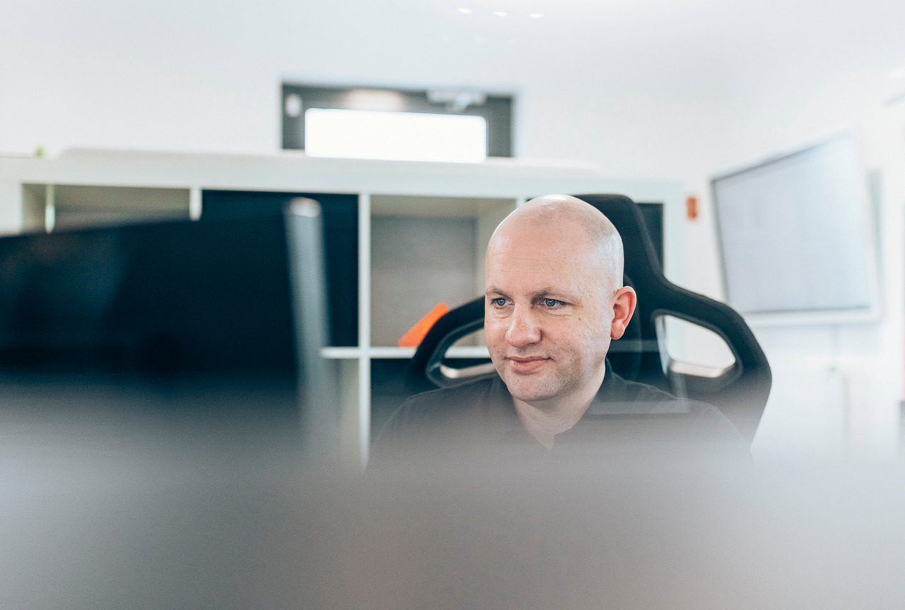 IT-Fachkraft sitzt an einem Arbeitsplatz in einem hellen Büro und prüft die Systeme